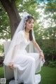 A woman in a wedding dress sitting on a chair.