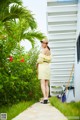 A woman in a yellow dress and hat walking down a sidewalk.