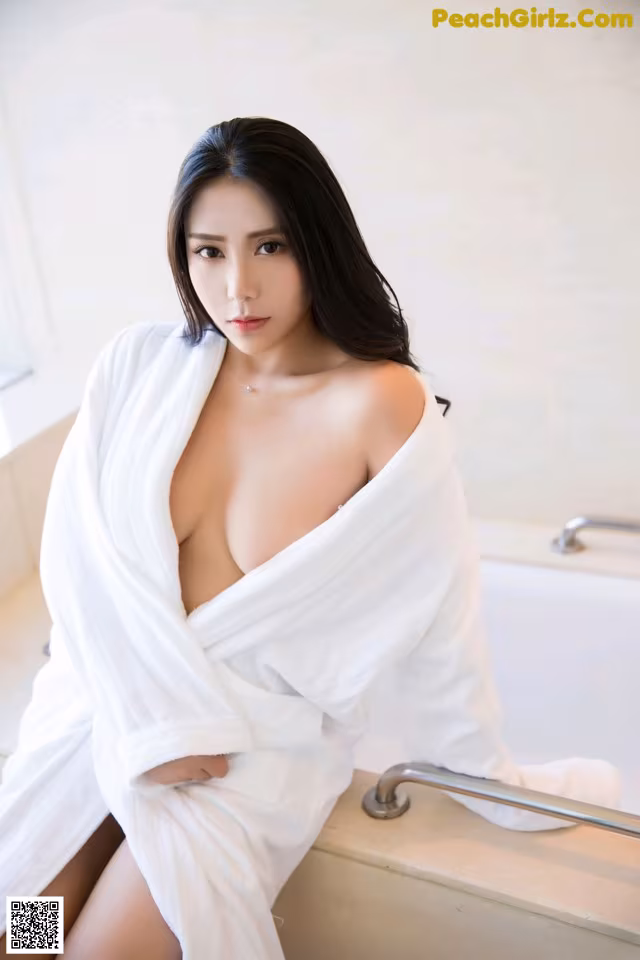 A woman in a white robe sitting in a bathtub.