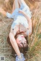 A woman laying in a field of tall grass.