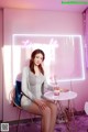 A woman sitting at a table in front of a neon sign.