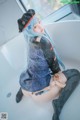 A woman with long blue hair sitting in a bathtub.