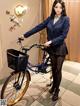 A woman in a school uniform standing next to a bicycle.