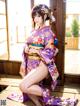 A woman in a purple kimono sitting on a wooden floor.