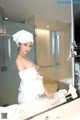 A woman in a white towel standing in front of a mirror.