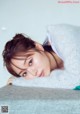 A young woman laying on top of a bed under a blanket.